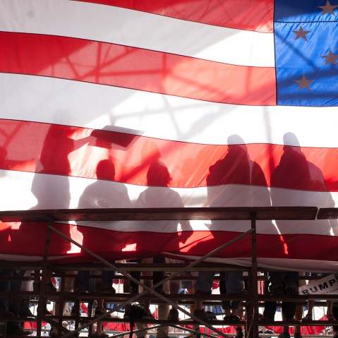 Supporters are seen backstage through an American flag during a Republican presidential candidate Donald Trump rally at the The Northwest Washington Fair and Event Center on May 7, 2016 in Lynden, Wash. (Photo by Matt Mills McKnight/Getty)