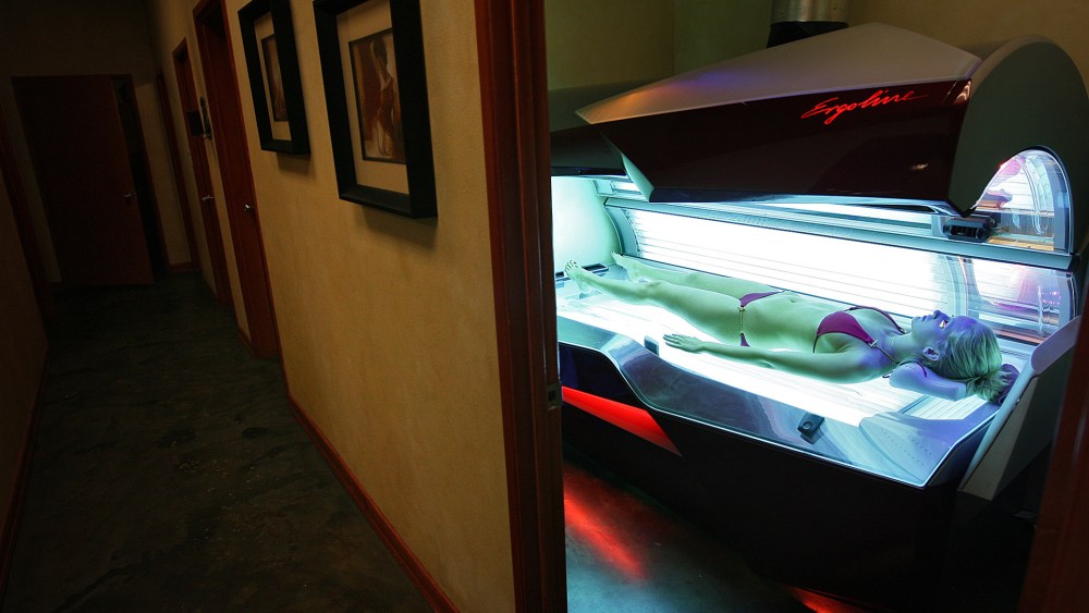Erika Greet, an employee of U-Tan, a tanning salon located near USC, demonstrates for a photographer the workings of an Ergoline Excellence tanning bed. (Photo by Robert Gauthier/Los Angeles Times/Getty)