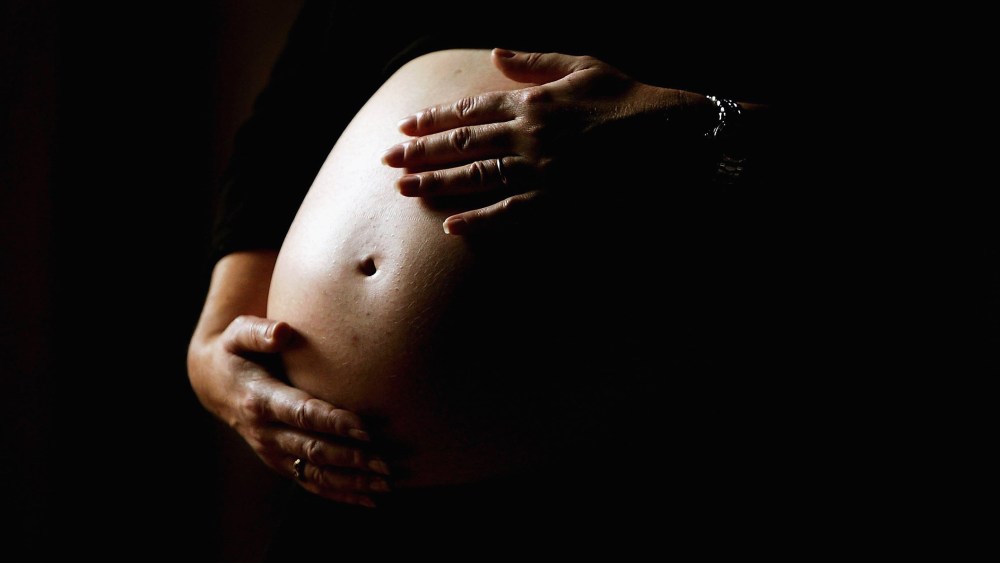 A pregnant woman holds her stomach, June 7, 2006. (Photo by Ian Waldie/Getty)