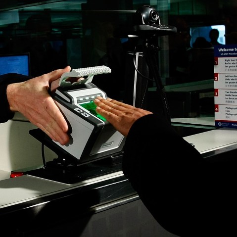 International airline passengers are fingerprinted on all ten fingers by a U.S. Customs and Border Protection officer on arrival at Dulles International Airport, Dec. 10, 2007 in Sterling, Va. (Photo by Win McNamee/Getty)