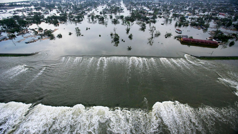 Water spills over a levee along the Inner Harbor Navigational Canal in the aftermath of Hurricane Katrina on Aug. 30, 2005 in New Orleans, La. (Photo by AFP/Getty)
