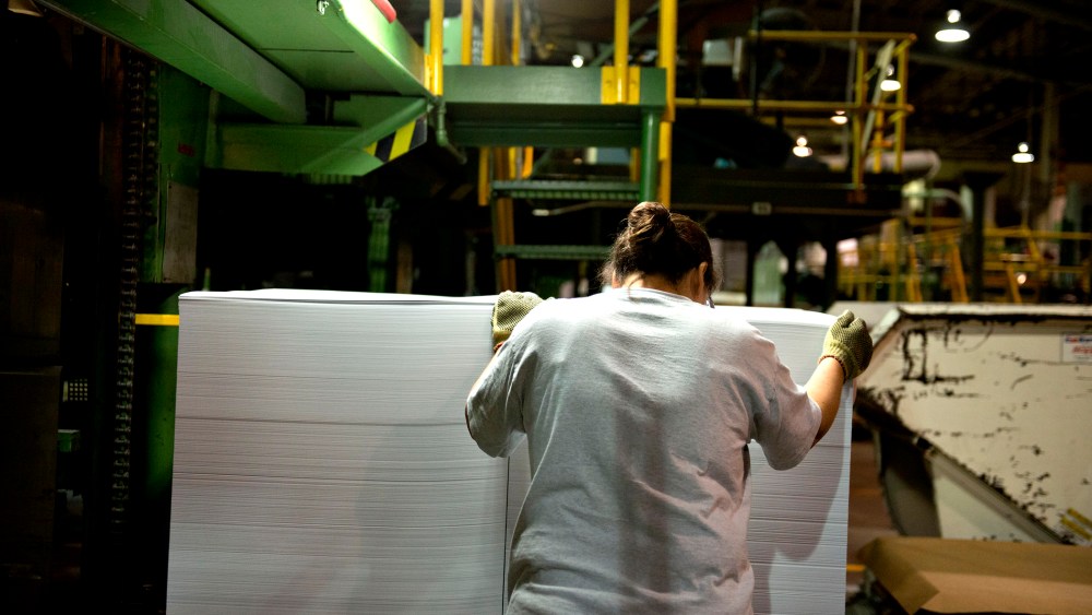An employee guides a stack of cut paper as it is unloaded from a cutting machine at a paper mill in Rothschild, Wisconsin, U.S., on Wednesday, Oct. 10, 2012.