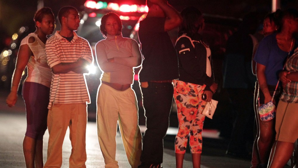 People gather in the 5100 block of S. Wood St. after multiple shooting victims are attended to and moved to waiting ambulances near Cornell Square Park in the Back of the Yards neighborhood of Chicago, September 19, 2013.