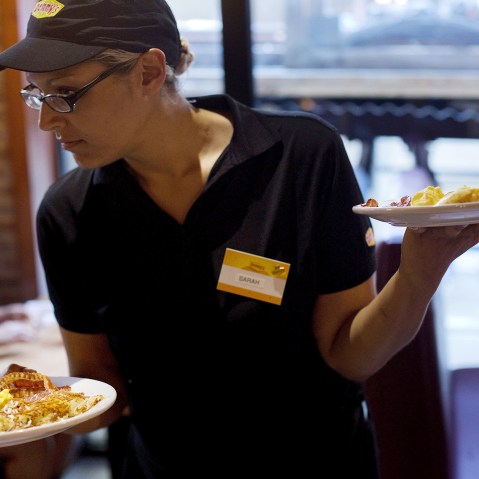 Waitress Sarah Ortiz delivers a tray of food to customers at a Denny's restaurant in New York, on Sept. 6, 2014.