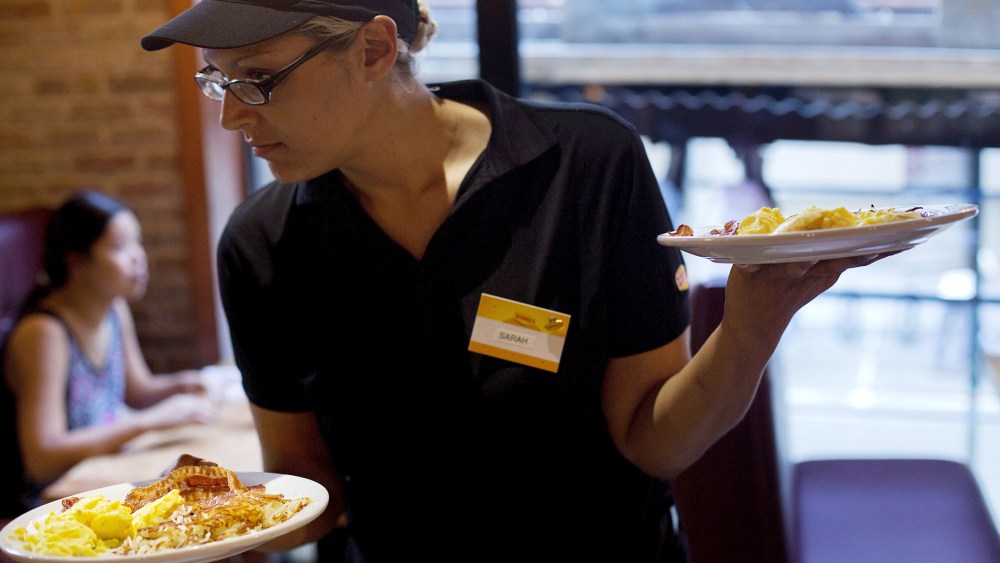 Waitress Sarah Ortiz delivers a tray of food to customers at a Denny's restaurant in New York, on Sept. 6, 2014.