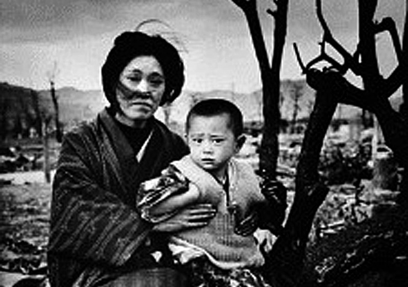 A mother and child, dressed in traditional clothing, sit on the ground amid rubble and brunt trees, Hiroshima, Japan, December 1945. On August 6, some four months previously, the United States had dropped an atomic bomb on the city--three days later a...