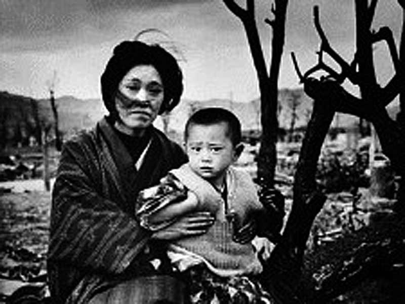 A mother and child, dressed in traditional clothing, sit on the ground amid rubble and brunt trees, Hiroshima, Japan, December 1945. On August 6, some four months previously, the United States had dropped an atomic bomb on the city--three days later a...