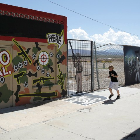 A young person runs by the Last Stop outdoor shooting range Wednesday, Aug. 27, 2014, in White Hills, Ariz. Gun range instructor Charles Vacca was accidentally killed Monday, Aug. 25, 2014 at the range by a 9-year-old with an Uzi submachine gun.