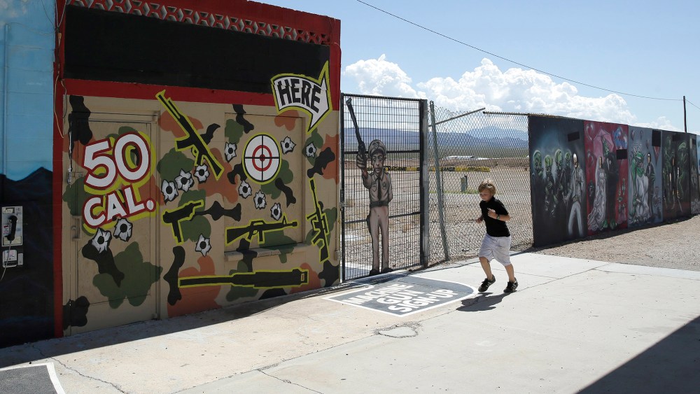 A young person runs by the Last Stop outdoor shooting range Wednesday, Aug. 27, 2014, in White Hills, Ariz. Gun range instructor Charles Vacca was accidentally killed Monday, Aug. 25, 2014 at the range by a 9-year-old with an Uzi submachine gun.