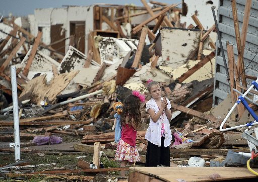 Two girls stand in rubble after a tornado struck Moore, Okla., May 20, 2013. A tornado tore through the Oklahoma City suburb of Moore on Monday, killing dozens while destroying entire tracts of homes, piling cars atop one another, and trapping school...