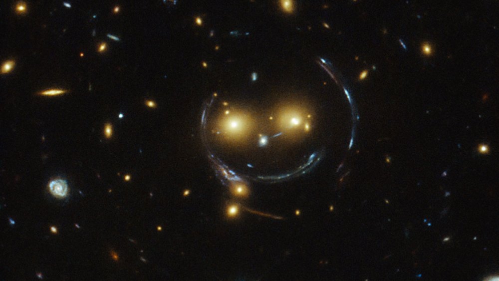 In the case of this "happy face," the two eyes are the galaxies SDSSCGB 8842.3 and SDSSCGB 8842.4 and the misleading smile lines are actually arcs caused by an effect known as strong gravitational lensing. February 9, 2015