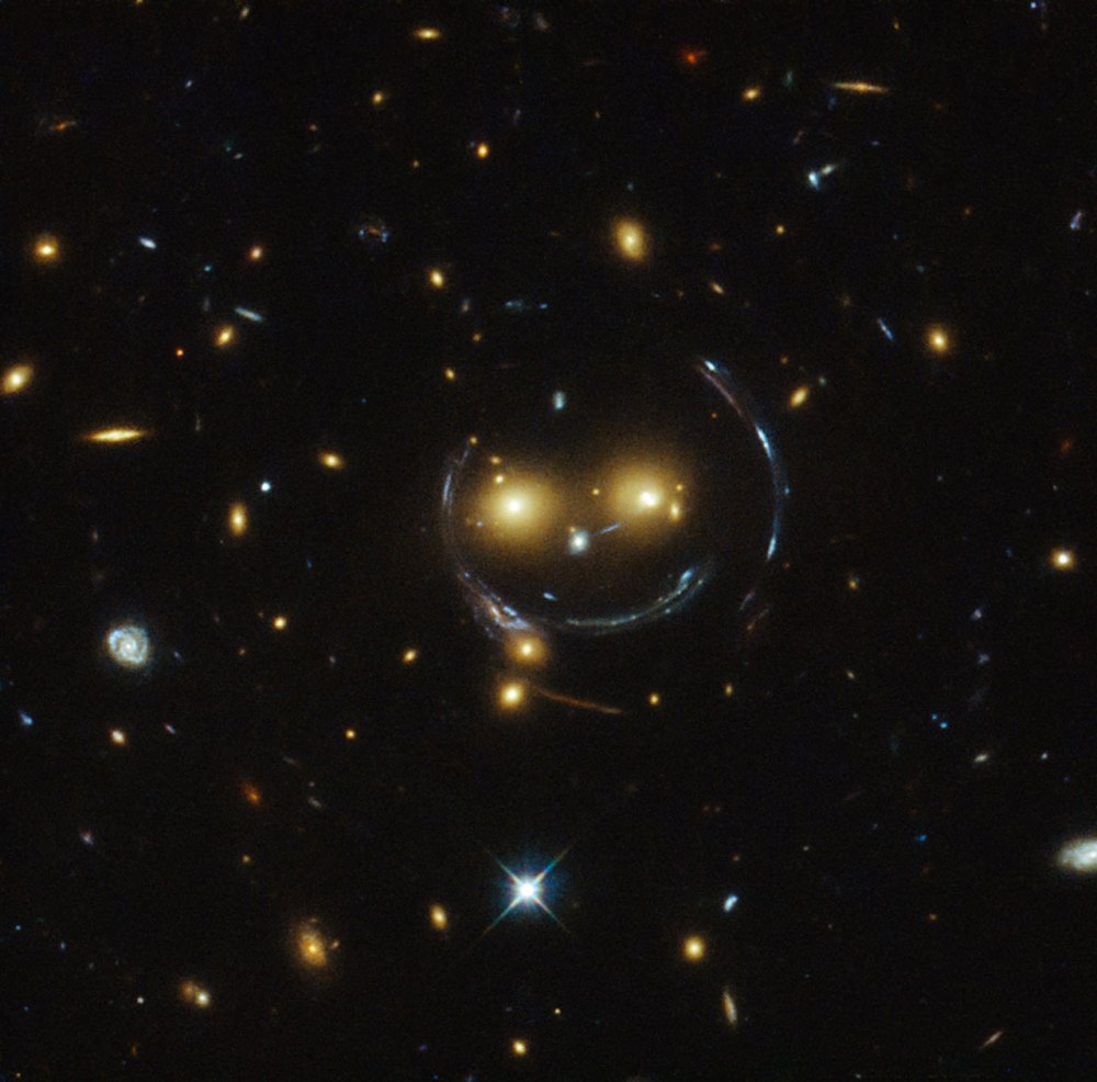 In the case of this "happy face," the two eyes are the galaxies SDSSCGB 8842.3 and SDSSCGB 8842.4 and the misleading smile lines are actually arcs caused by an effect known as strong gravitational lensing. February 9, 2015