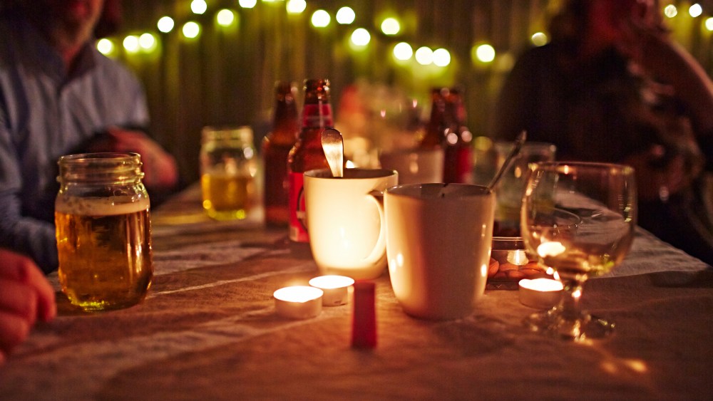 People sitting at table with candles and drinks.