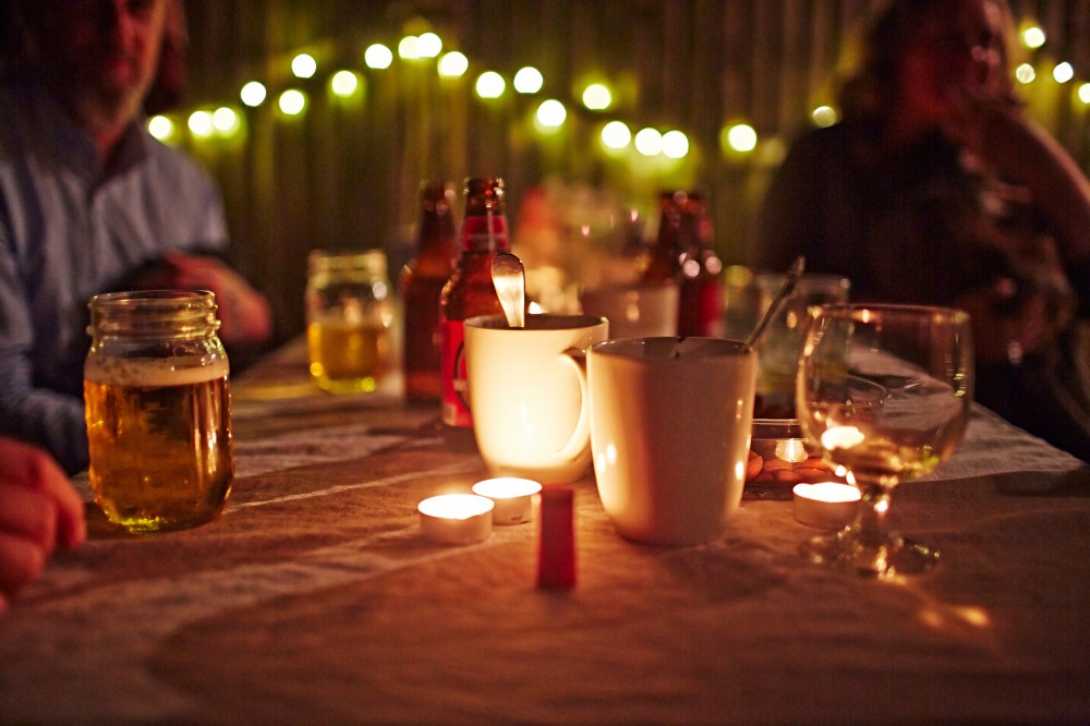 People sitting at table with candles and drinks.