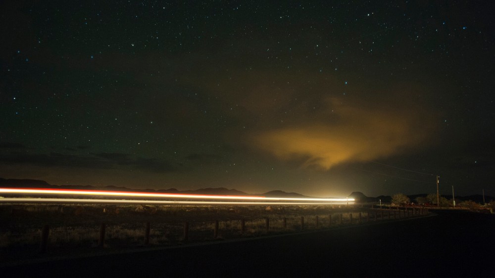 A car drives down the highway at night under a sky full of stars. (Photo by Justin Carrasquillo/Gallery Stock)