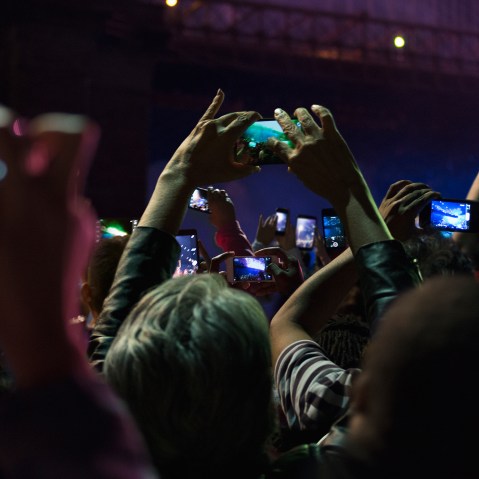 People in crowd take photos on their cell phones at night. (Photo by GS/Gallery Stock)