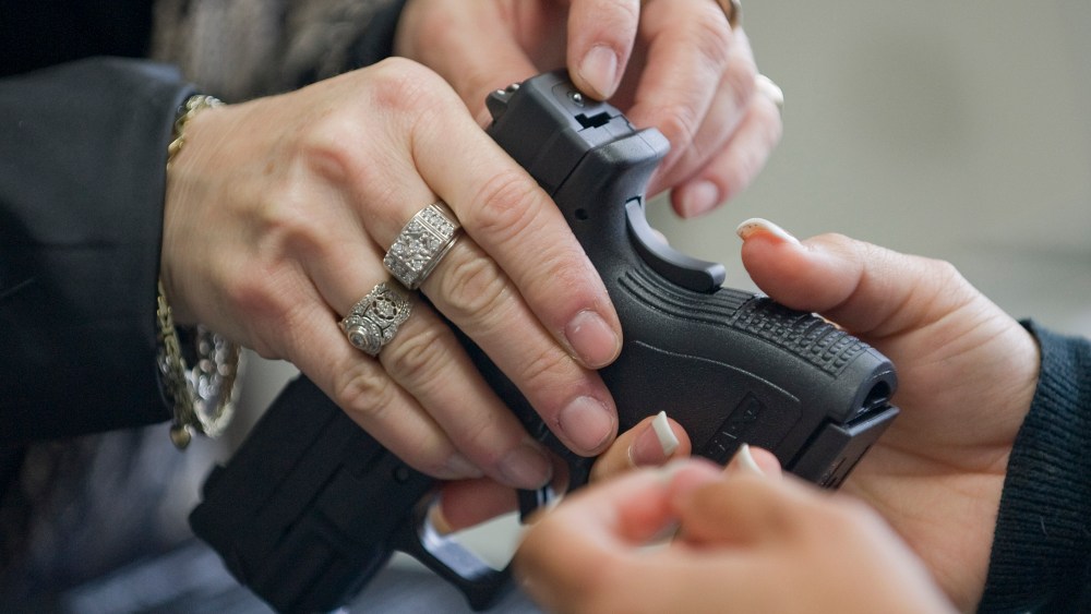 At Ade's Gun Shop & Em & M Guns in Orange, Emily Atkinson shows the safety features of a Springfield Armory XD compact pistol to a female client on Dec. 6, 2012.(AP Photo/The Orange County Register, Jebb Harris)