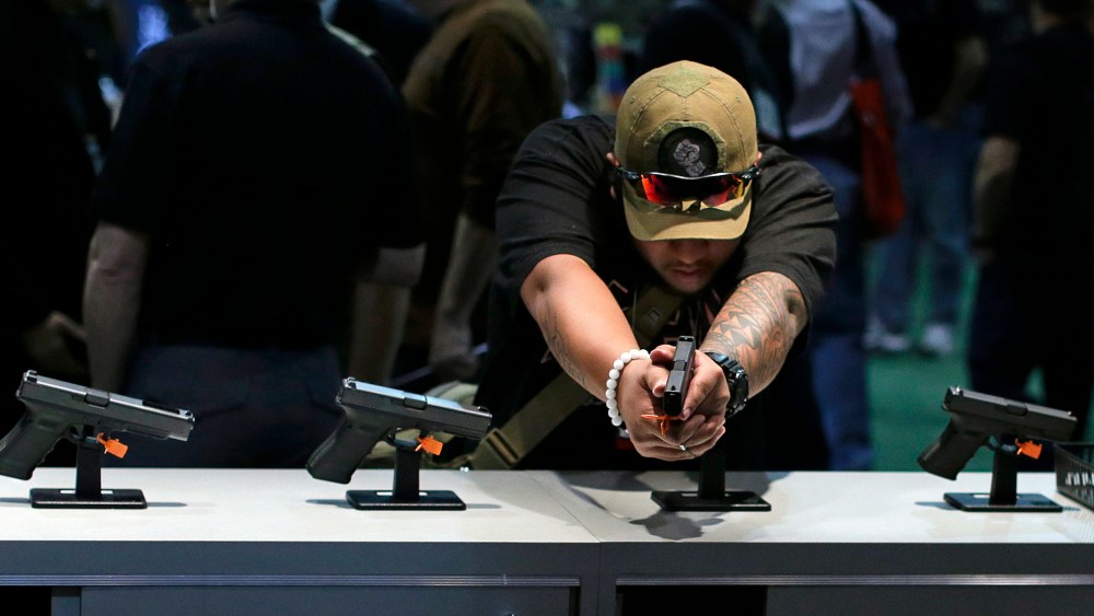 Firearms buyer Joshua Asperila checks out various Glock hand guns on display during the Shooting Hunting and Outdoor Trade Show,  Tuesday, Jan. 14, 2014, in Las Vegas.