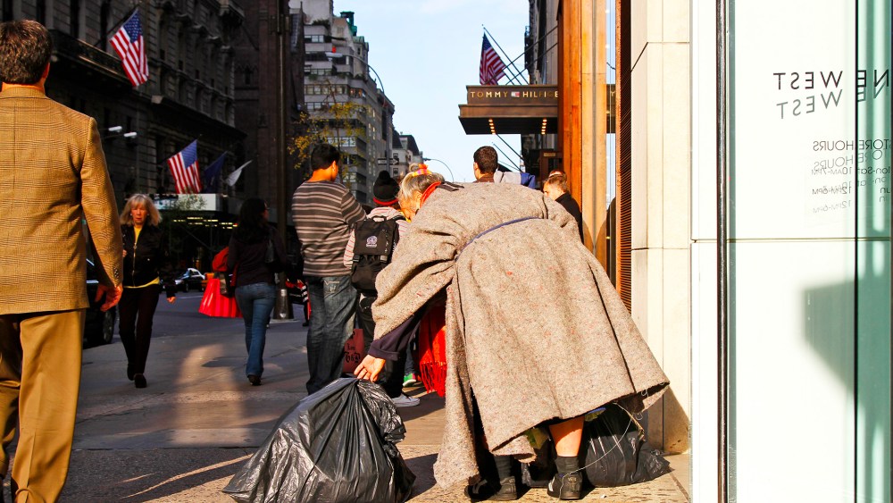 A homeless women walks among shoppers on 5th Avenue in Manhattan.