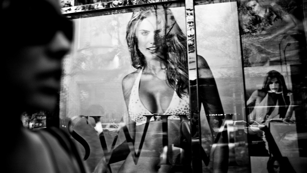 A window reflection of a woman passing by the Victoria's Secret store in Chicago.