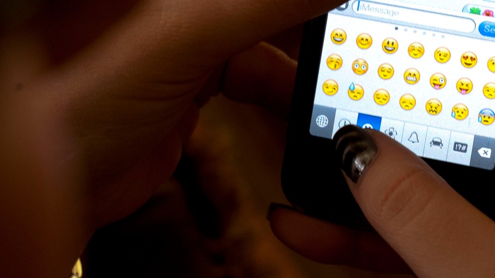 An iPhone owner uses emoji icons while texting.