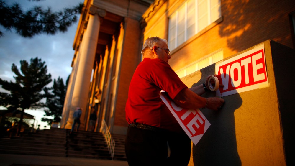 A poll worker posts signs at a polling station, Feb. 28, 2012, in Phoenix, Ariz.