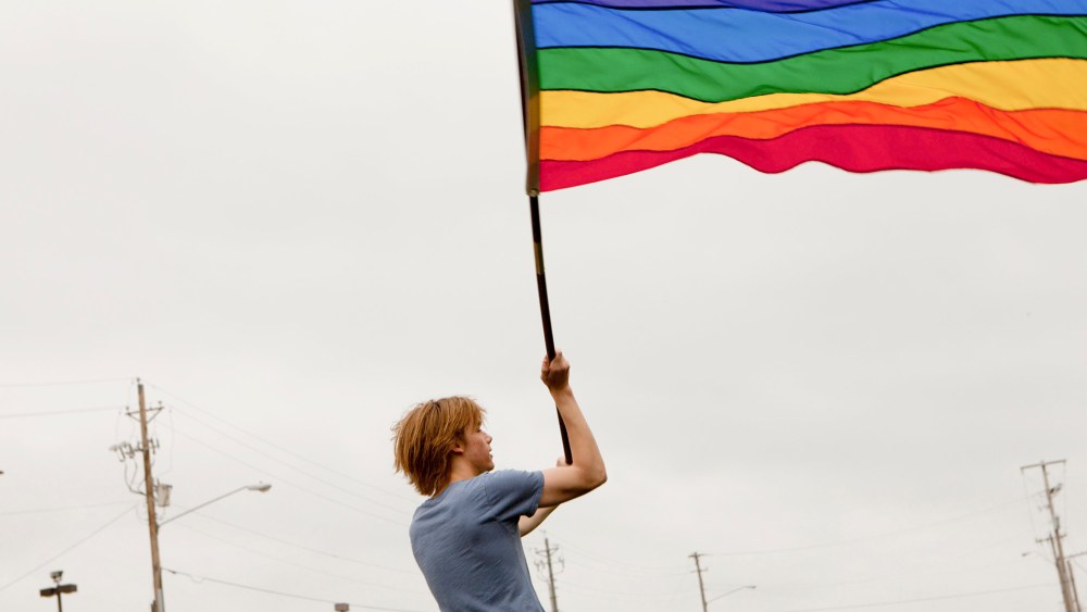 Gay rights protester Bob Gilchrist waves a flag outside the Hilton hotel in Jackson, Miss., March 8, 2012.