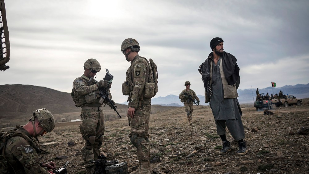 Soldiers from the 101st Airborne Division stand next to an Afghan suspected of Taliban connections in Lakaray, Afghanistan, April 14, 2013.
