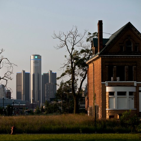 Early morning light falls on an a vacant, boarded up house as downtown Detroit is seen in the background, a day after the city filed for bankruptcy protection in court, in Detroit, on July 19, 2013.