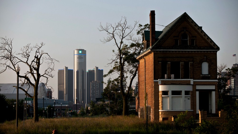 Early morning light falls on an a vacant, boarded up house as downtown Detroit is seen in the background, a day after the city filed for bankruptcy protection in court, in Detroit, on July 19, 2013.