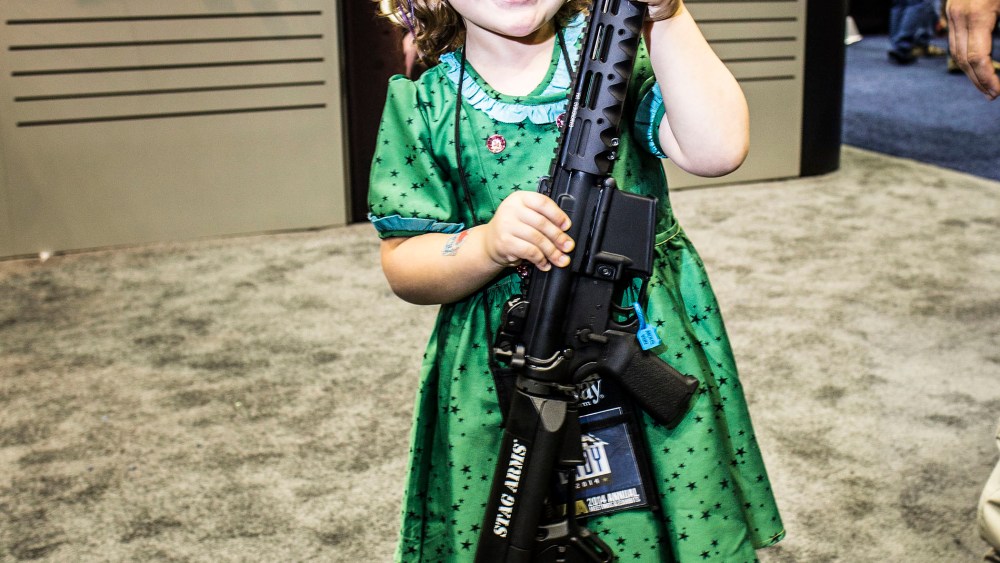 A four year old girl poses for a photo with an assault rifle at the NRA's annual convention in Indianapolis, Indiana, April 2014.
