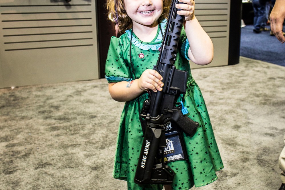 A four year old girl poses for a photo with an assault rifle at the NRA's annual convention in Indianapolis, Indiana, April 2014.
