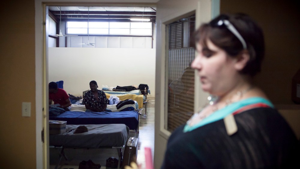Residents at the Randy Sam's Outreach Shelter sit on their cots as Jennifer Laurent, right, the shelter's executive director, walks by, in Texarkana, Texas.