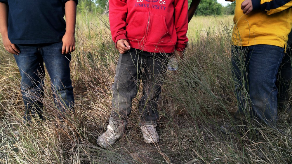 Three young boys wait as Border Patrol agents process a group of 22 migrants who have just crossed the Rio Grande near McAllen, Texas.