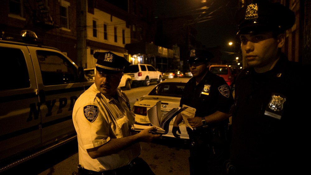 Police officers on scooters watch children playing at night outside a housing project in the Brooklyn borough of New York.