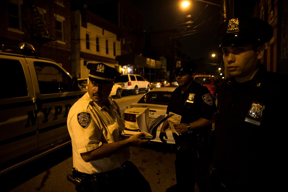 Police officers on scooters watch children playing at night outside a housing project in the Brooklyn borough of New York.