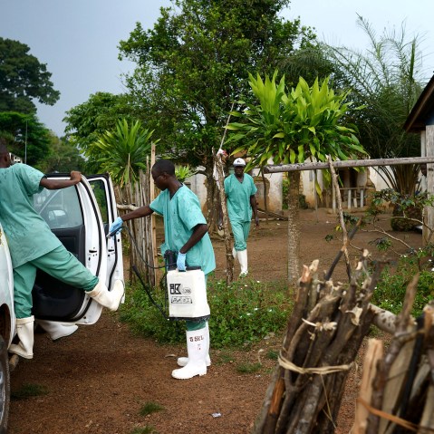 Doctors Without Borders workers wearing protective clothing disinfect materials at a clinic in Teldou, Guinea, July 10, 2014.