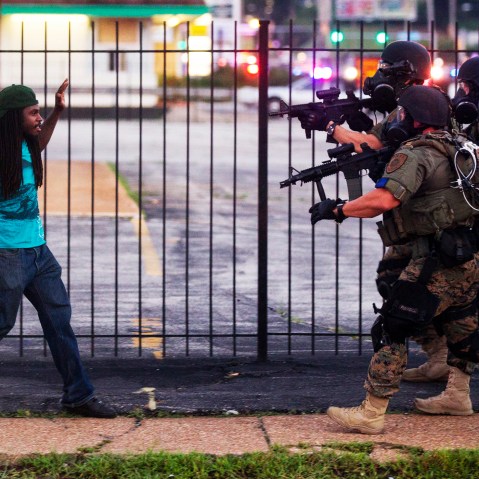 A man backs away as law enforcement officials close in on him and eventually detain him during protests over the death of Michael Brown, an unarmed black teenager killed by a police officer, in Ferguson, Mo., Aug. 11, 2014.