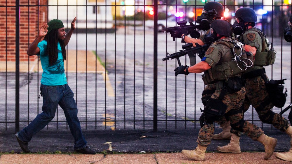 A man backs away as law enforcement officials close in on him and eventually detain him during protests over the death of Michael Brown, an unarmed black teenager killed by a police officer, in Ferguson, Mo., Aug. 11, 2014.