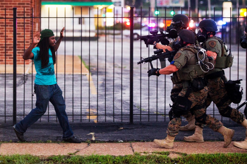 A man backs away as law enforcement officials close in on him and eventually detain him during protests over the death of Michael Brown, an unarmed black teenager killed by a police officer, in Ferguson, Mo., Aug. 11, 2014.