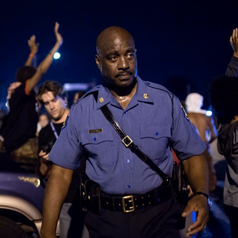 Capt. Ron Johnson of the Missouri State Highway Patrol walks through a crowd of demonstrators along West Florissant Avenue in Ferguson, Mo.