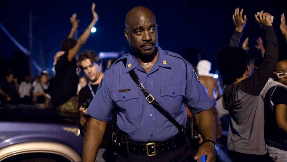Capt. Ron Johnson of the Missouri State Highway Patrol walks through a crowd of demonstrators along West Florissant Avenue in Ferguson, Mo.