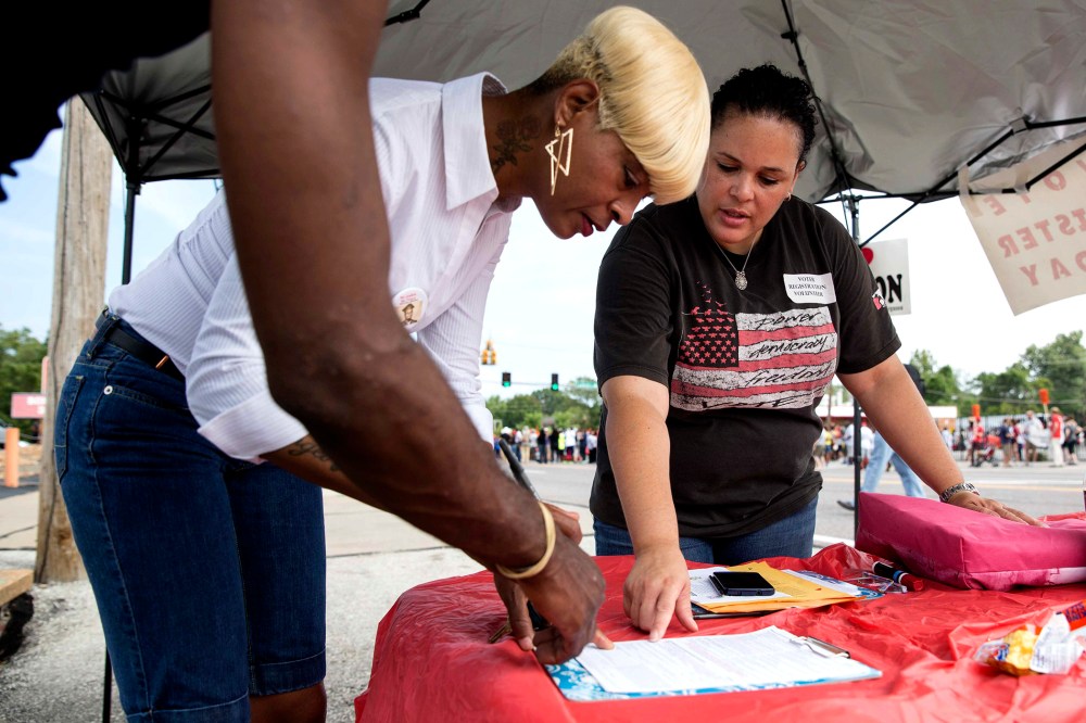 Shiron Hagens, right, helps resident Rita Foley register to vote at a rally in Ferguson, Mo., Aug. 30, 2014.