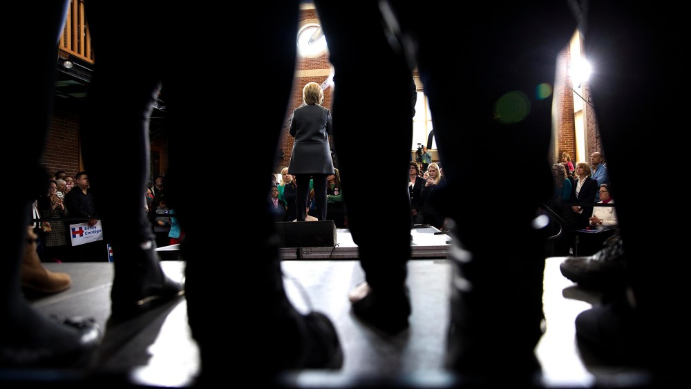 Seen through the legs of attendees, Hillary Clinton, a Democratic presidential hopeful, speaks during a campaign event at the Lyman and Merrie Wood Museum of Springfield History in Springfield, Mass.