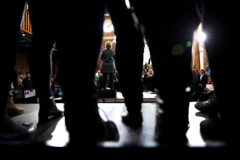 Seen through the legs of attendees, Hillary Clinton, a Democratic presidential hopeful, speaks during a campaign event at the Lyman and Merrie Wood Museum of Springfield History in Springfield, Mass.