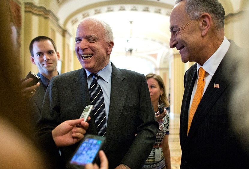 Republican Senator from Arizona John McCain (L) and Democratic Senator from New York Chuck Schumer (R) talk with the media outside the Senate chamber after the immigration bill passed a crucial vote to move forward to a final vote in the US Capitol in...