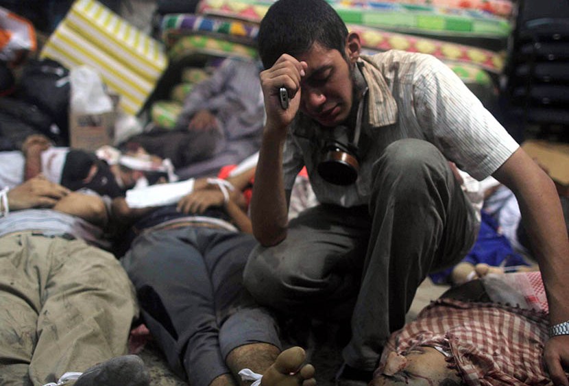 A young man mourns next to the bodies of protesters killed during the clearing of one of the two sit-ins of ousted president Morsi supporters, at the field hospital, near Rabaa Adawiya mosque, in Cairo, Egypt, on August 14, 2013. (Photo by Mosaab...