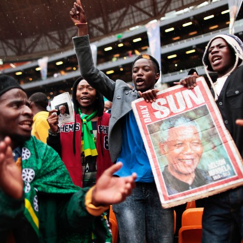 Supporters of late South African president Nelson Mandela sing and dance in the rain as they arrive to attend the memorial service in Johannesburg, Dec. 10, 2013.