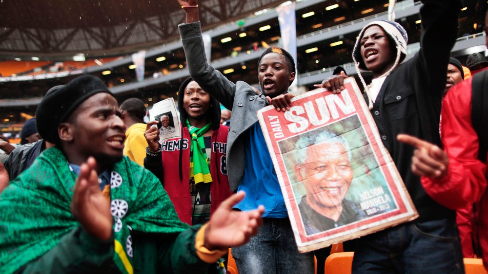 Supporters of late South African president Nelson Mandela sing and dance in the rain as they arrive to attend the memorial service in Johannesburg, Dec. 10, 2013.