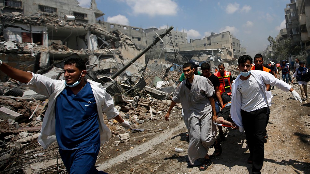 Palestinian paramedics lift the body of a man from the Al Shejaeiya neighborhood, during a brief period of ceasefire requested by local rescue forces to retrieve dead and wounded from the Shuja'iyya neighborhood in east Gaza City, July 20, 2014.